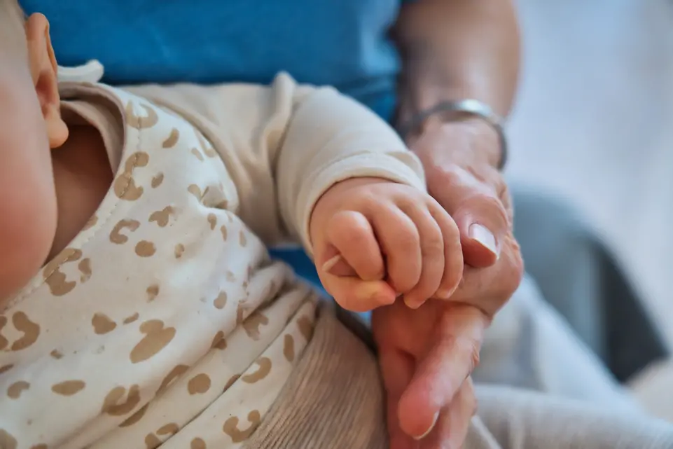 Hand eines Babys h&auml;lt die Finger eines Erwachsenen