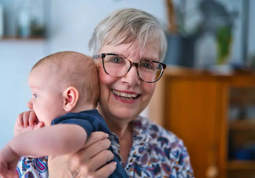 &Auml;ltere Frau h&auml;lt ein Baby im Arm
