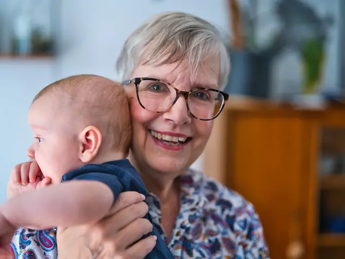 &Auml;ltere Frau h&auml;lt ein Baby im Arm