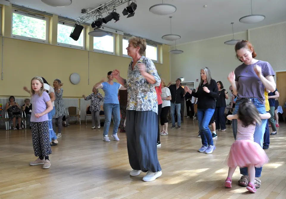Erwachsene und Kinder tanzen in einem Saal