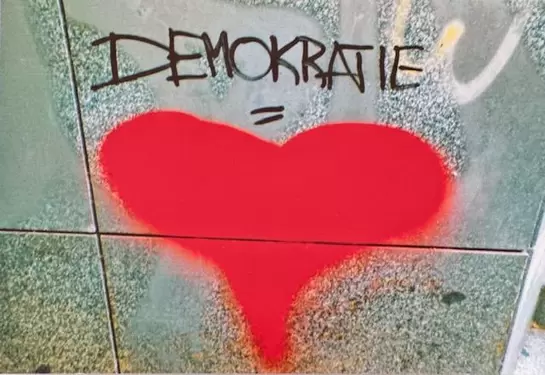 Ein gespr&uuml;htes Herz mit der &Uuml;berschrift Demokratie auf einer Wand