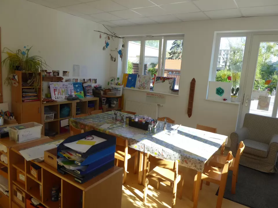 Raum mit Tischen und St&uuml;hlen und Regalen mit Arbeitsmaterialien an den W&auml;nden und im Raum