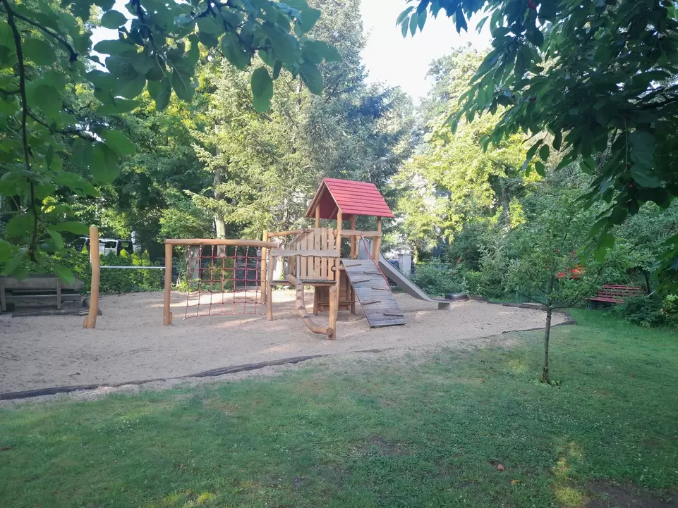 gr&uuml;ner Garten mit Sandkasten und Kletterturm in der Mitte