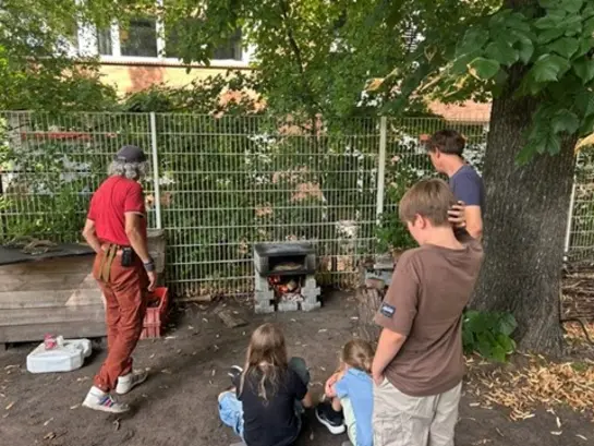 Kinder stehen vor einem Pizzaofen im Garten