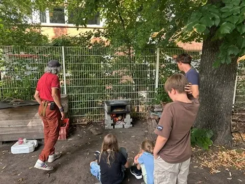 Kinder stehen vor Pizzaofen im Garten