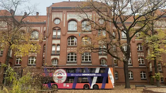 Ein bunter Bus vor einem Schulgeb&auml;ude
